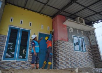 Ilustrasi petugas PLN saat melakukan perbaikan meter listrik rumah warga pasca terendam banjir.