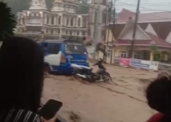 Warga sedang mengabadikan banjir bandang yang melanda kota Parapat, Simalungun, Minggu (16/3/2025) sore. Foto Tangkapan layar